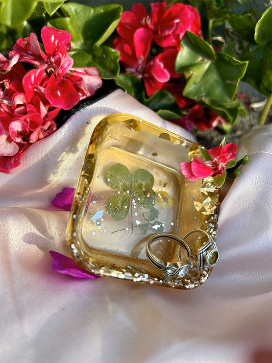 Gold glitter and four leaf clover jewelry tray shown with rings