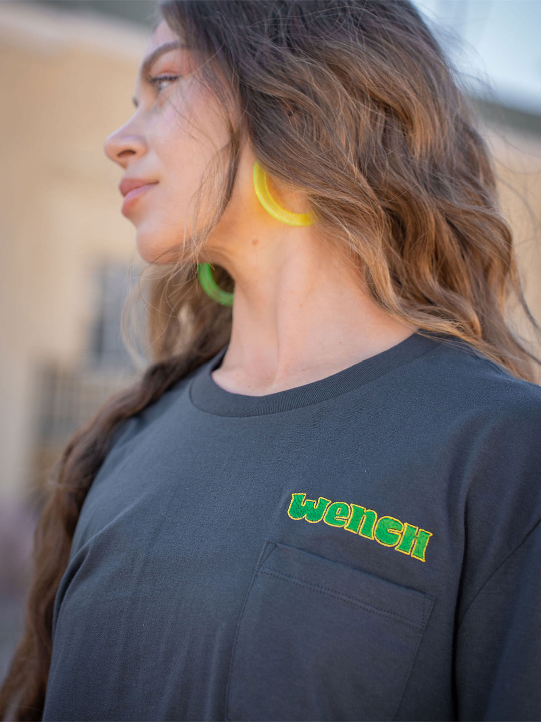 Wenches 2024 Unisex Pocket Tee Green Yellow Logo Front Close Up